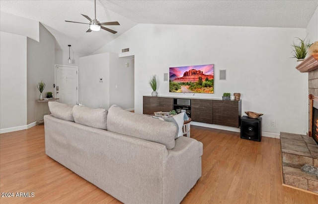 living room featuring light hardwood / wood-style floors, a textured ceiling, ceiling fan, and vaulted ceiling