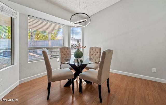 dining room featuring a textured ceiling and wood-type flooring