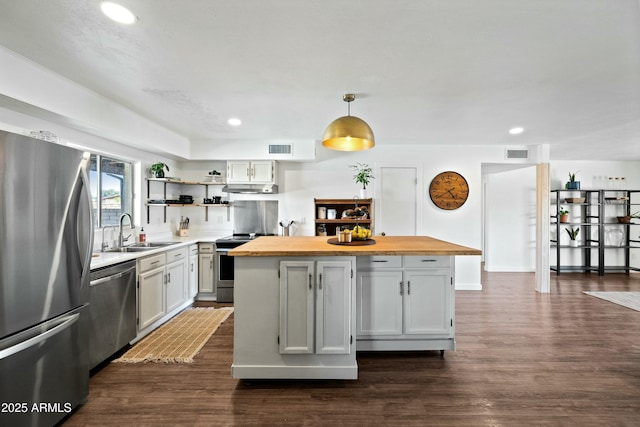 kitchen with stainless steel appliances, butcher block countertops, a sink, and visible vents