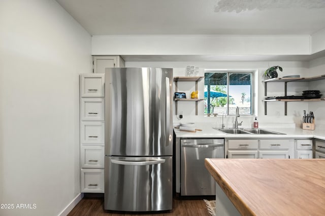 kitchen featuring dark wood-style flooring, open shelves, light countertops, appliances with stainless steel finishes, and a sink