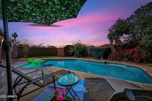 view of swimming pool with a storage shed, a fenced in pool, a patio, a fenced backyard, and an outdoor structure