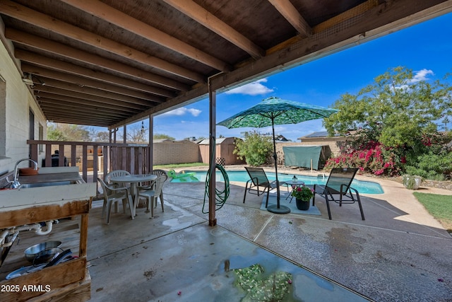 view of patio / terrace featuring a fenced in pool, an outbuilding, a storage unit, a sink, and a fenced backyard