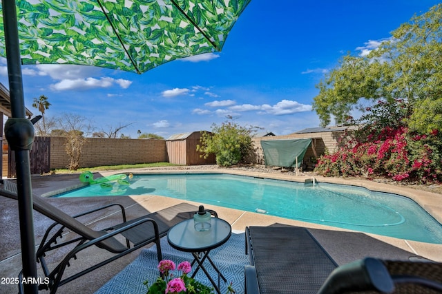 view of pool featuring a fenced backyard, an outdoor structure, a fenced in pool, a shed, and a patio area