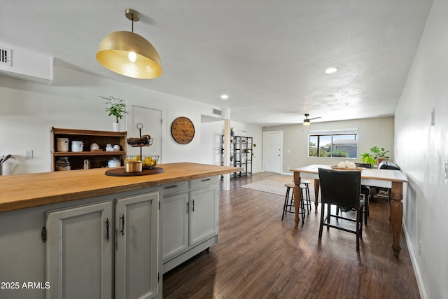 kitchen featuring dark wood-style floors, visible vents, wooden counters, hanging light fixtures, and baseboards