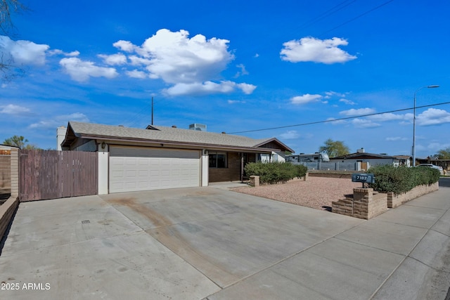 ranch-style house featuring driveway, an attached garage, and fence