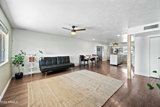 living room with a textured ceiling, visible vents, and dark wood-type flooring