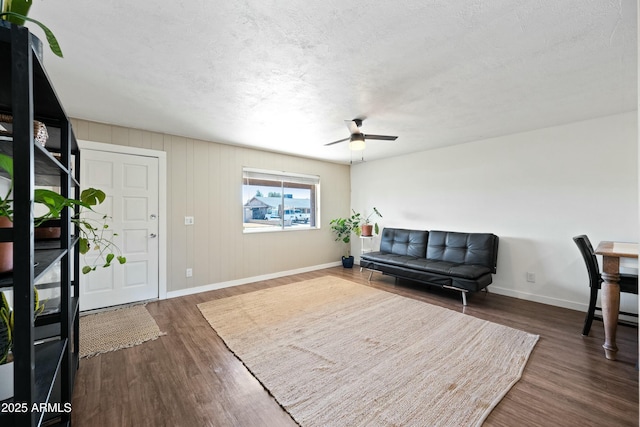 interior space with a textured ceiling, ceiling fan, wood finished floors, and baseboards