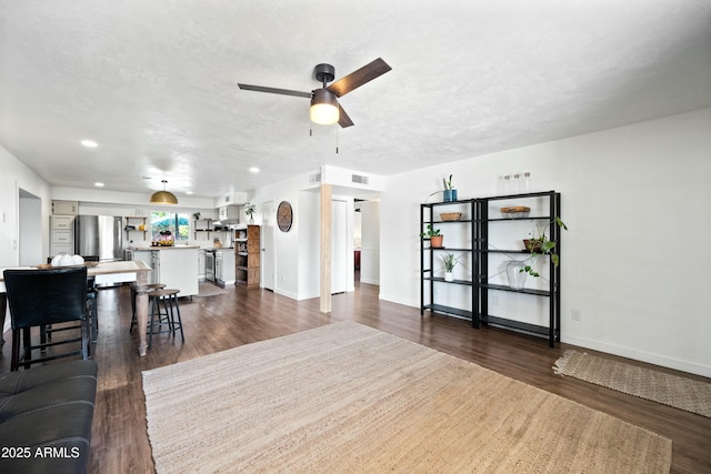 living room featuring ceiling fan, a textured ceiling, visible vents, and dark wood-type flooring