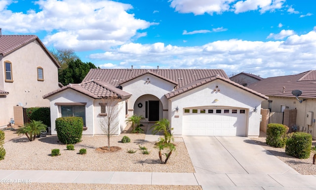 mediterranean / spanish-style house with a garage, concrete driveway, a tile roof, and stucco siding