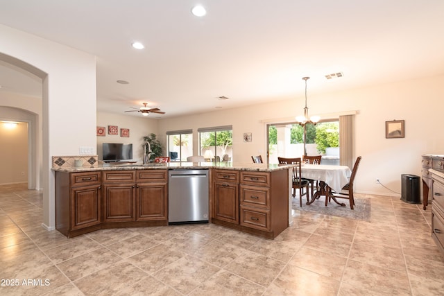 kitchen featuring light stone counters, pendant lighting, visible vents, stainless steel dishwasher, and brown cabinetry