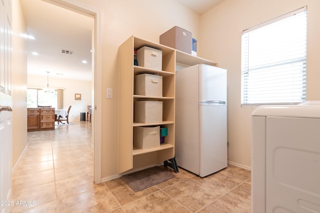 clothes washing area featuring light tile patterned floors, visible vents, an inviting chandelier, washer / dryer, and laundry area