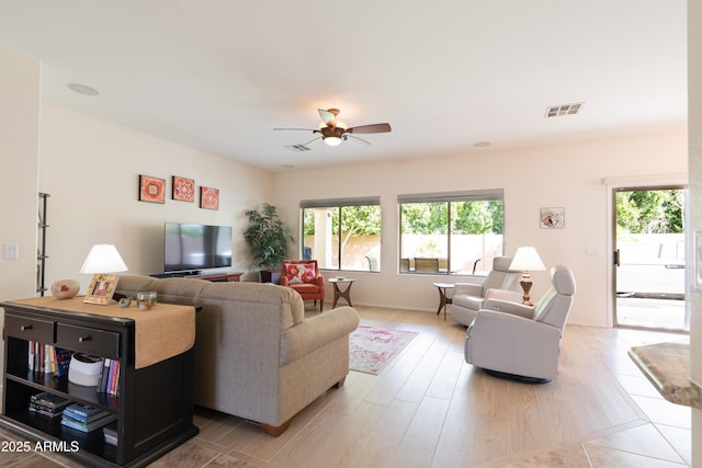 living room with light wood-style flooring, visible vents, and a ceiling fan