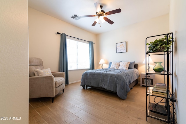 bedroom with light wood-style floors, baseboards, visible vents, and a ceiling fan