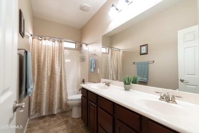 bathroom featuring double vanity, a sink, toilet, and tile patterned floors