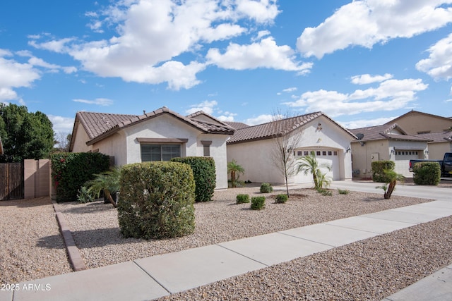 view of front facade featuring an attached garage, a tile roof, concrete driveway, and stucco siding