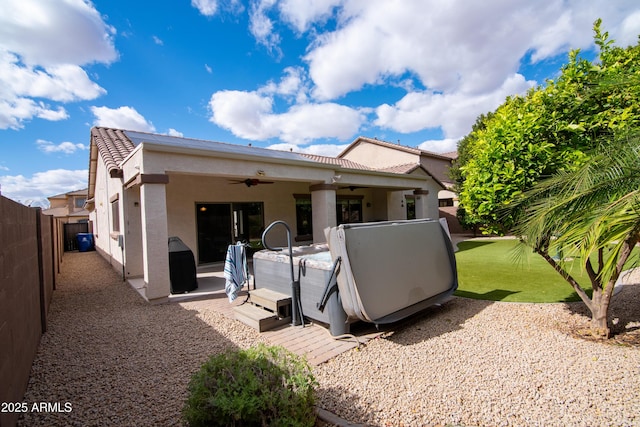 rear view of property with a patio, stucco siding, a hot tub, a ceiling fan, and a fenced backyard