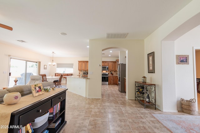 living room with arched walkways, light tile patterned floors, visible vents, and recessed lighting