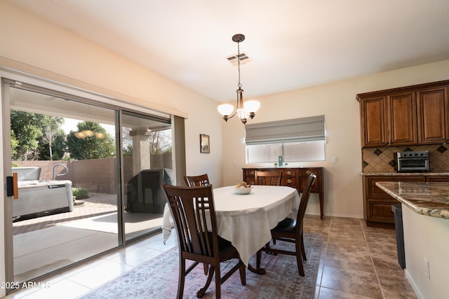 dining space featuring light tile patterned floors, a toaster, visible vents, baseboards, and an inviting chandelier