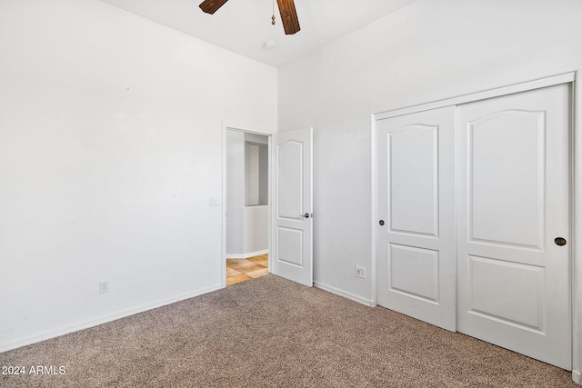 unfurnished bedroom featuring ceiling fan, a closet, and light carpet