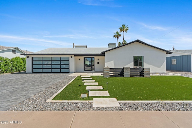 view of front of home with decorative driveway, a garage, a front lawn, and stucco siding