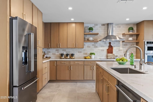 kitchen featuring wall chimney range hood, open shelves, appliances with stainless steel finishes, a sink, and tasteful backsplash