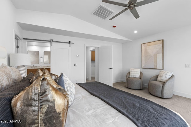 bedroom featuring visible vents, lofted ceiling, baseboards, ensuite bathroom, and a barn door