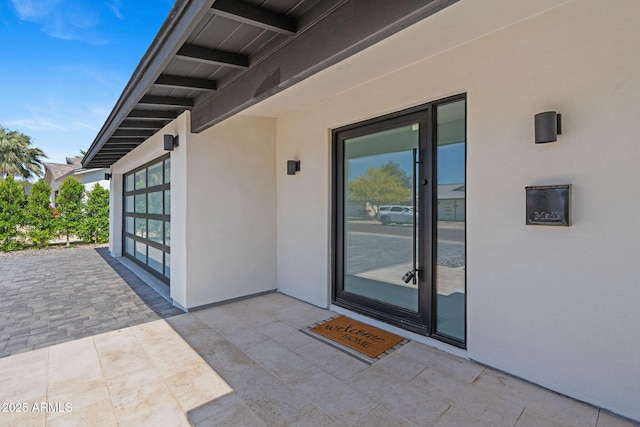view of exterior entry featuring a patio and stucco siding