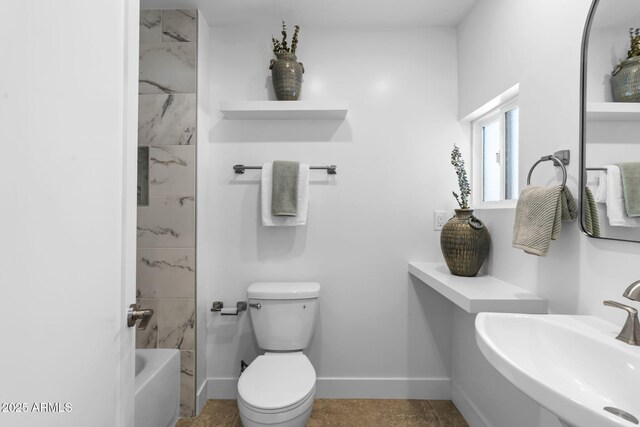 bathroom featuring baseboards, a sink, and toilet