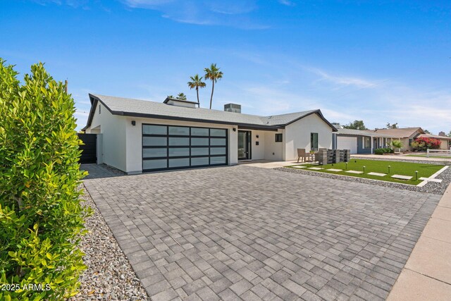 view of front of house featuring a garage, a front lawn, fence, decorative driveway, and stucco siding