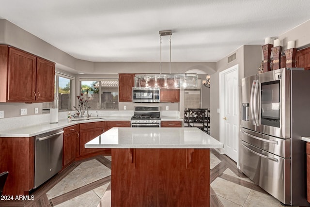 kitchen with sink, hanging light fixtures, a breakfast bar, a kitchen island, and appliances with stainless steel finishes