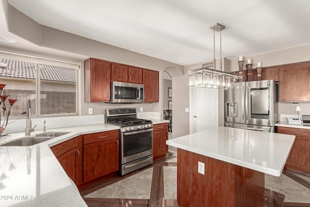 kitchen with appliances with stainless steel finishes, sink, a kitchen island, hanging light fixtures, and light tile patterned flooring