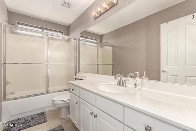 full bathroom with tile patterned flooring, vanity, combined bath / shower with glass door, and toilet