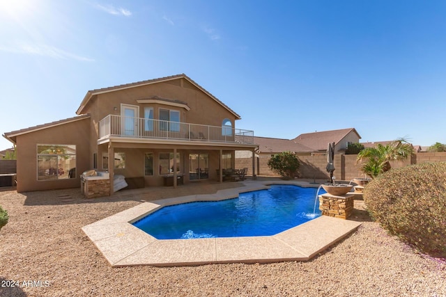 back of property with pool water feature, a patio area, a balcony, and a fenced in pool