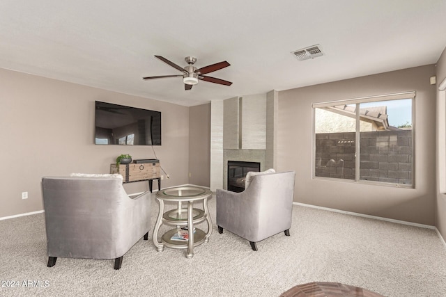 carpeted living room featuring ceiling fan and a fireplace