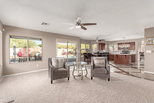 carpeted living room featuring ceiling fan with notable chandelier