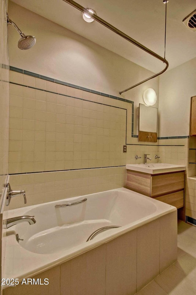 full bath featuring visible vents, tiled shower / bath combo, vanity, and tile walls