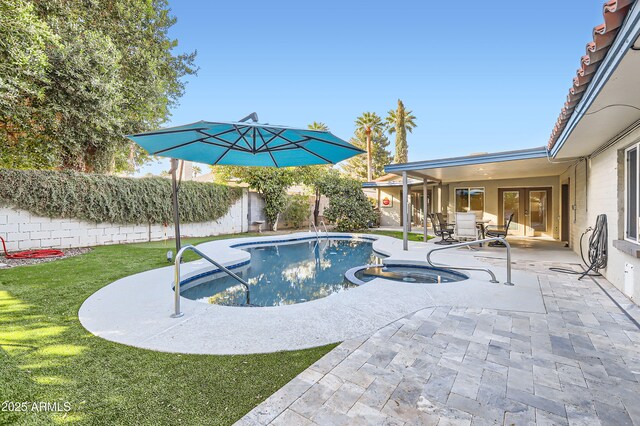 view of pool featuring a patio, a yard, a fenced backyard, and a pool with connected hot tub