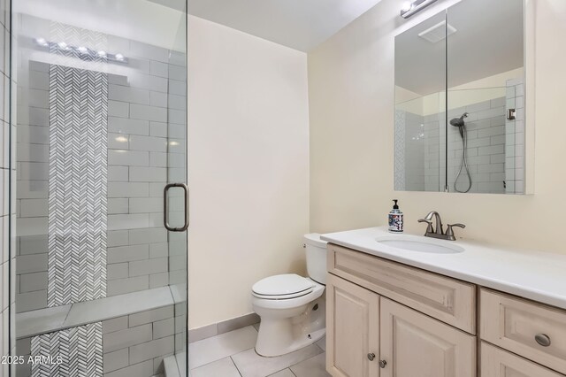 bathroom with a stall shower, baseboards, toilet, tile patterned flooring, and vanity