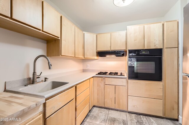 kitchen featuring under cabinet range hood, light brown cabinetry, and oven