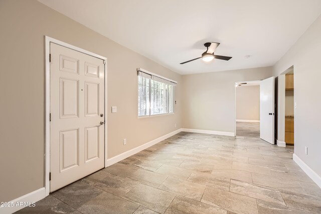 unfurnished room with ceiling fan and baseboards