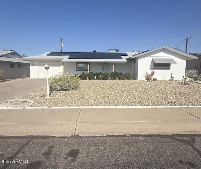 ranch-style house with a garage and solar panels