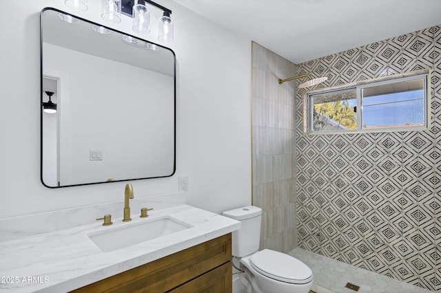 bathroom featuring vanity, toilet, and a tile shower