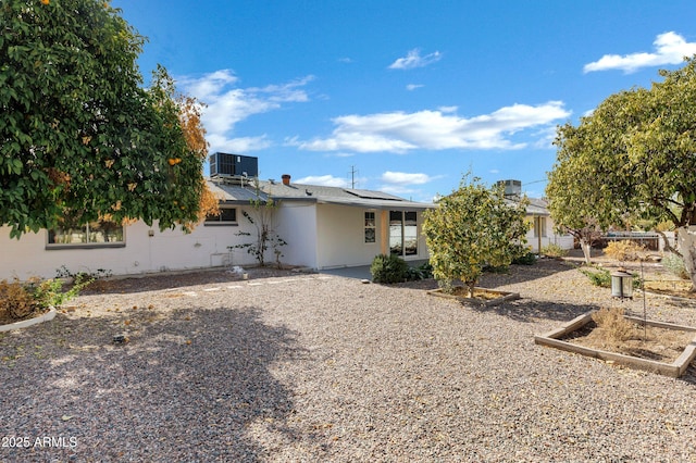 rear view of property featuring cooling unit and solar panels