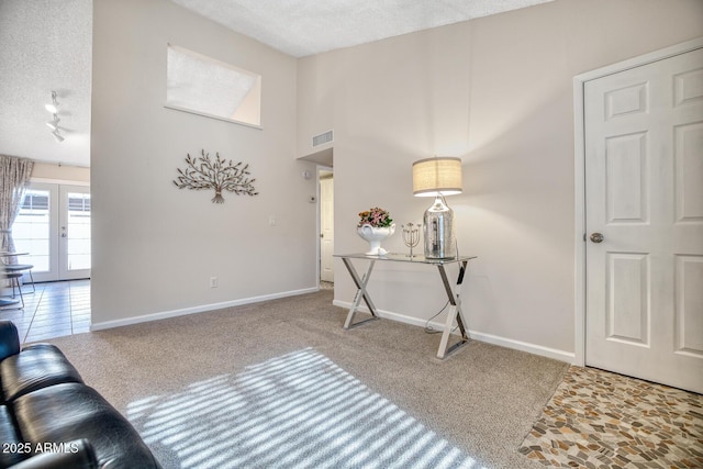 foyer featuring track lighting, carpet floors, a textured ceiling, and french doors