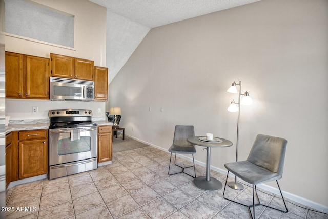 kitchen with light tile patterned flooring, stainless steel appliances, a textured ceiling, and high vaulted ceiling