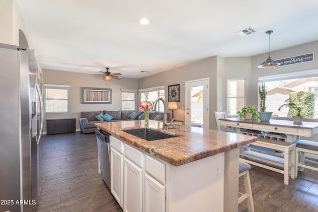 kitchen with visible vents, white cabinets, a sink, an island with sink, and stainless steel appliances