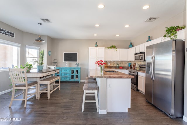 kitchen with white cabinets, a sink, visible vents, and stainless steel appliances