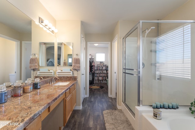 bathroom with baseboards, a walk in closet, a shower stall, vanity, and wood finished floors