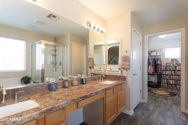 bathroom with a shower stall, wood finished floors, a sink, and visible vents