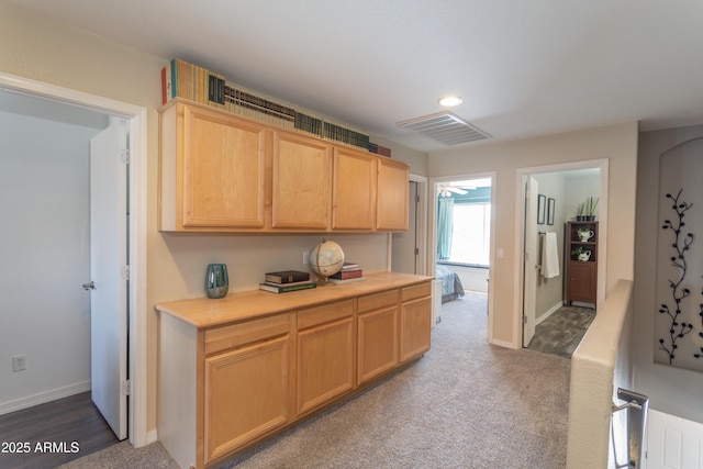 kitchen featuring light brown cabinetry, visible vents, dark colored carpet, light countertops, and baseboards